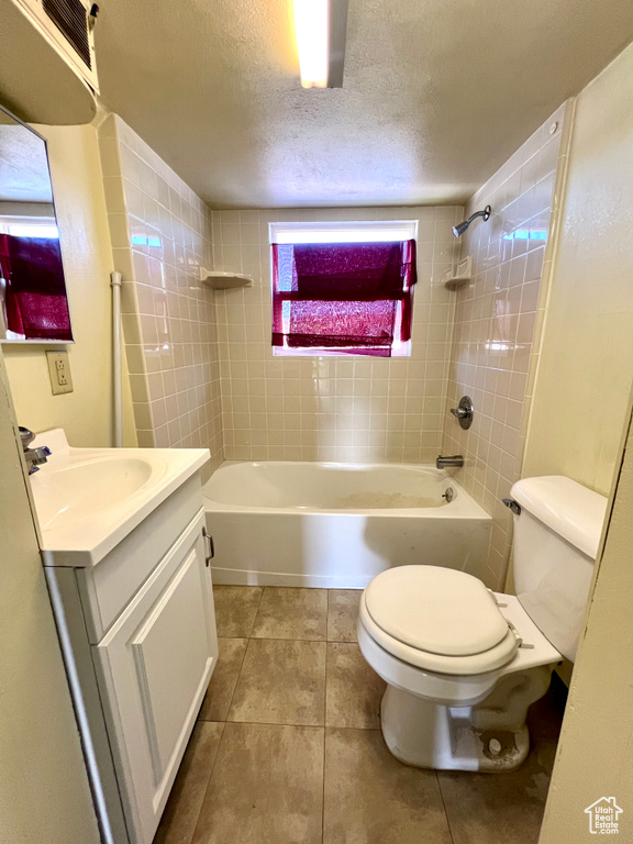 Full bath featuring toilet, vanity, a textured ceiling, tile patterned flooring, and shower / bath combination