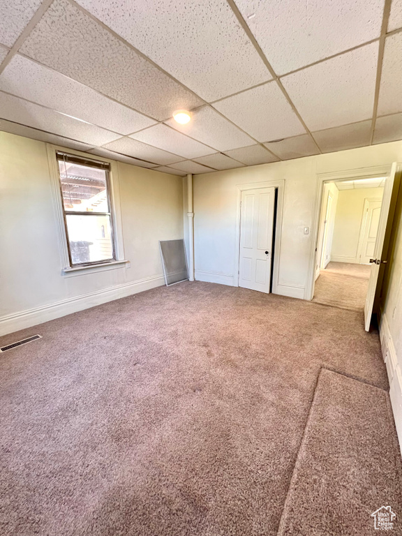 Unfurnished bedroom featuring a paneled ceiling, carpet flooring, and baseboards