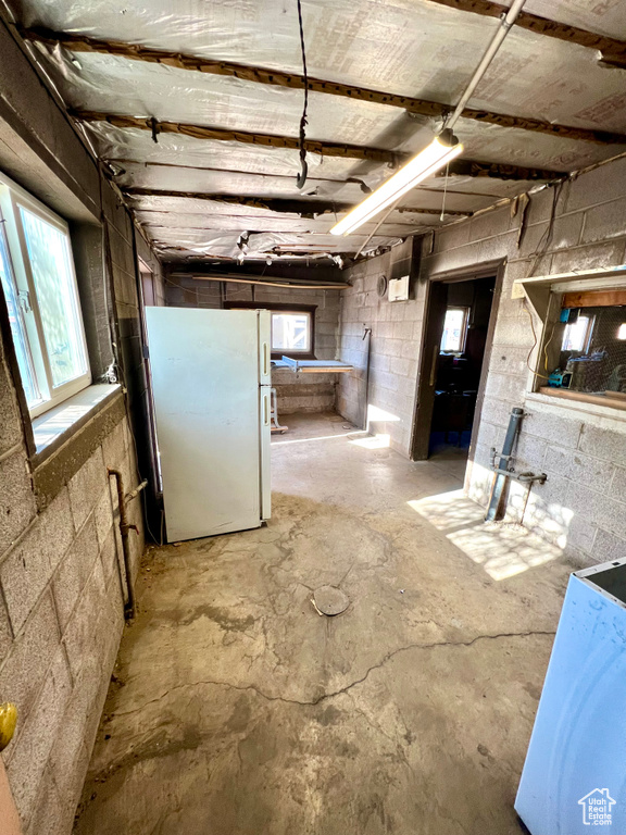 Below grade area with freestanding refrigerator, concrete block wall, and plenty of natural light