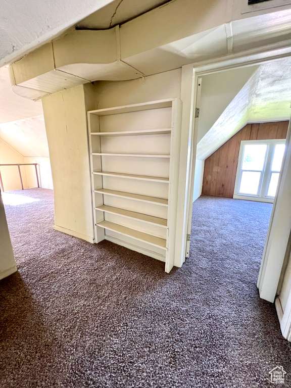 Corridor with carpet floors and vaulted ceiling