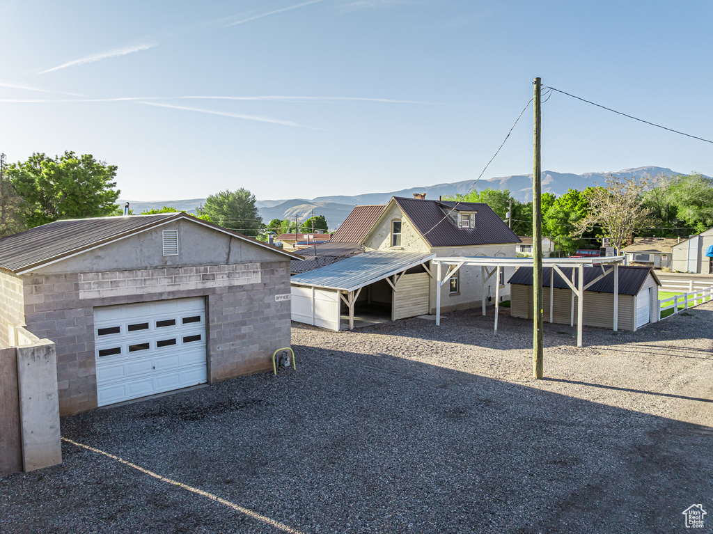 View of front of property featuring an outdoor structure, a mountain view, a detached garage, and driveway