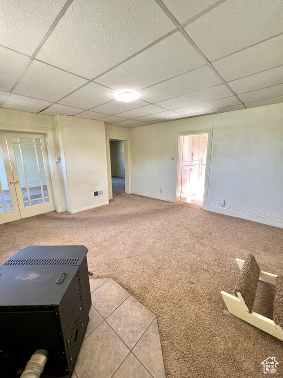 Spare room featuring a drop ceiling, carpet, and baseboards