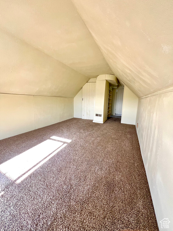 Bonus room with lofted ceiling, carpet flooring, and a textured ceiling