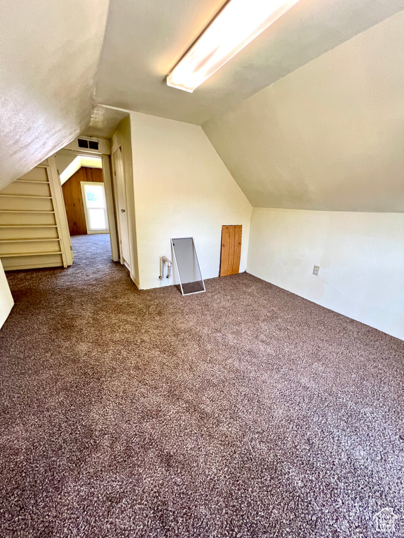 Bonus room featuring vaulted ceiling and dark colored carpet