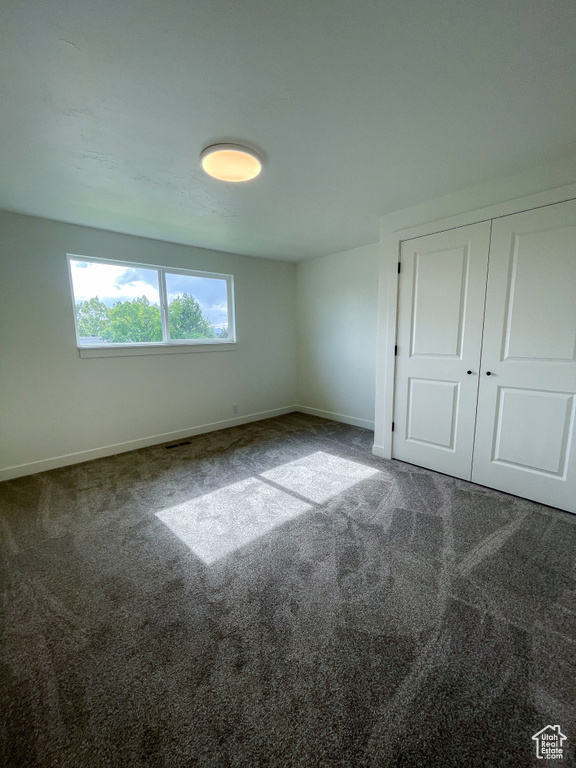 Unfurnished bedroom featuring baseboards, carpet, and a closet
