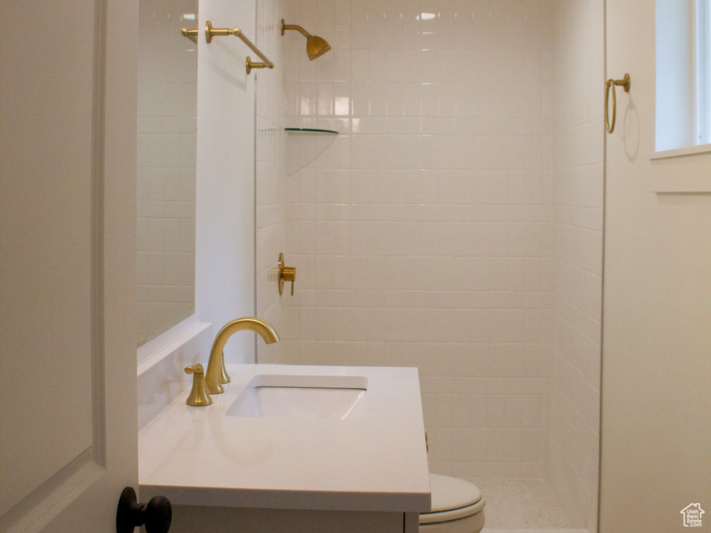 Full bathroom featuring vanity, a tile shower, toilet, wood finished floors, and recessed lighting