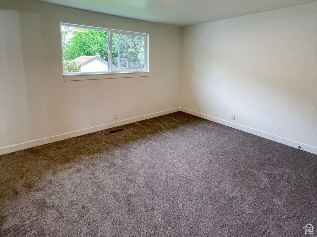 Empty room with dark carpet and baseboards