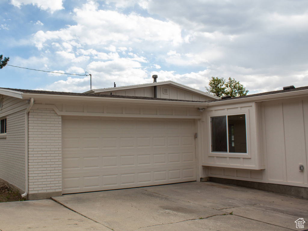 View of side of property with board and batten siding, brick siding, and concrete driveway