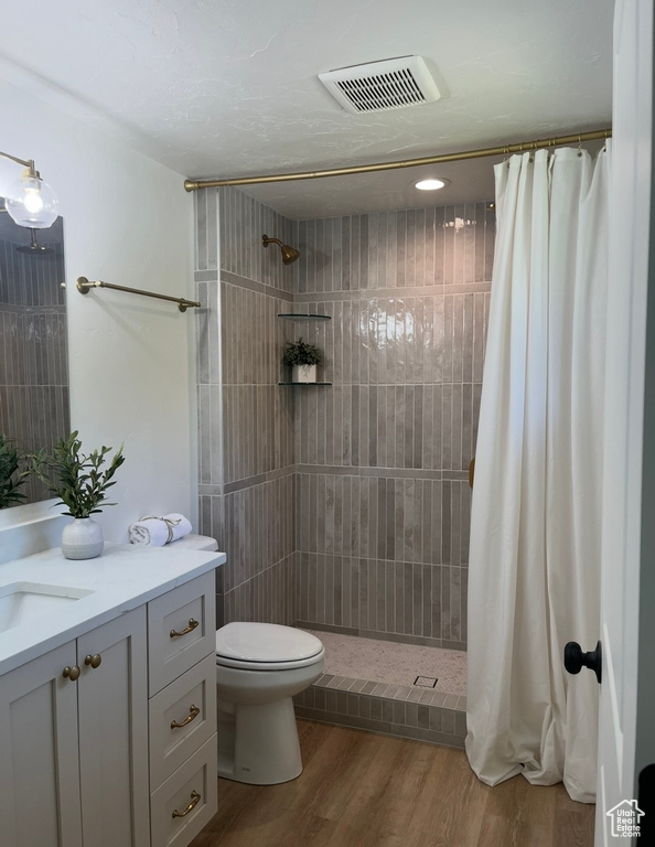 Bathroom with vanity, a tile shower, and wood finished floors