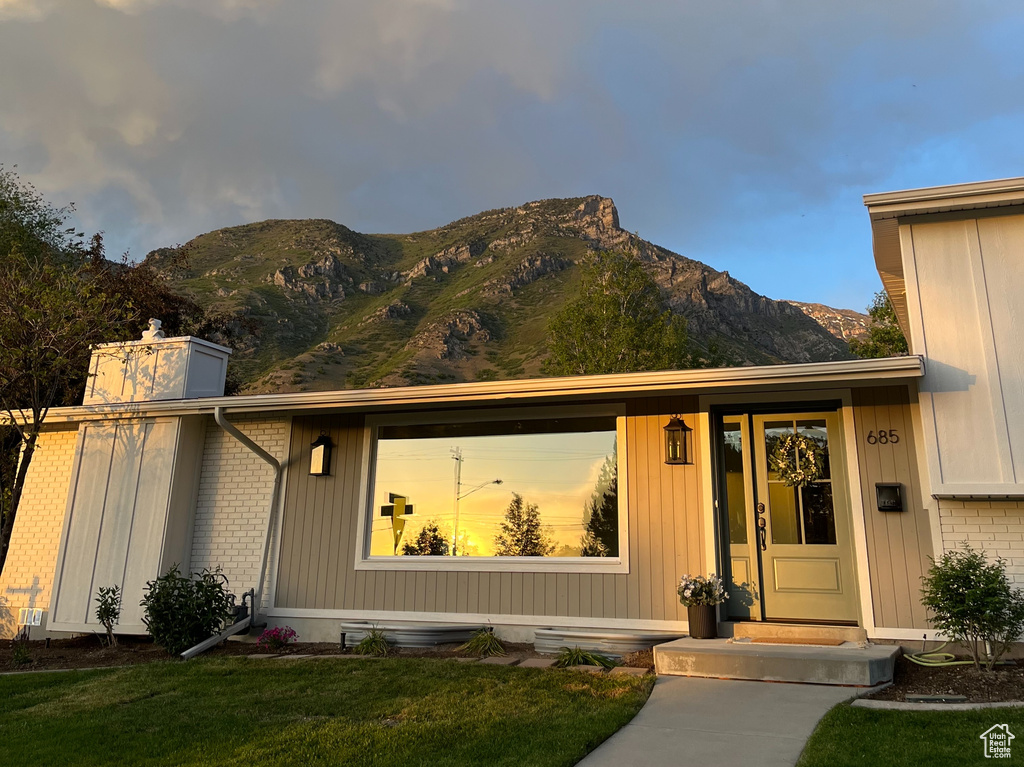 View of front of property with a mountain view, a front yard, and board and batten siding