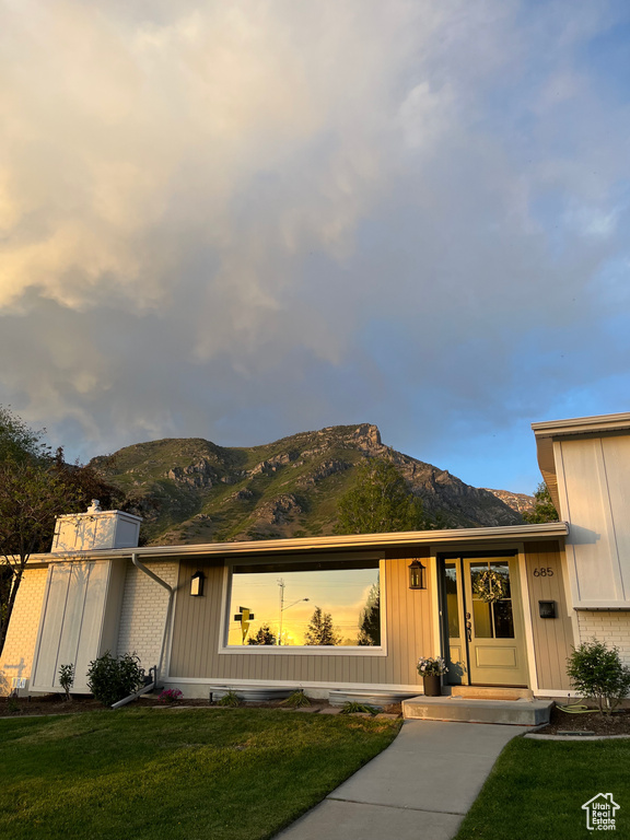 View of front of property with a mountain view, a front yard, and board and batten siding