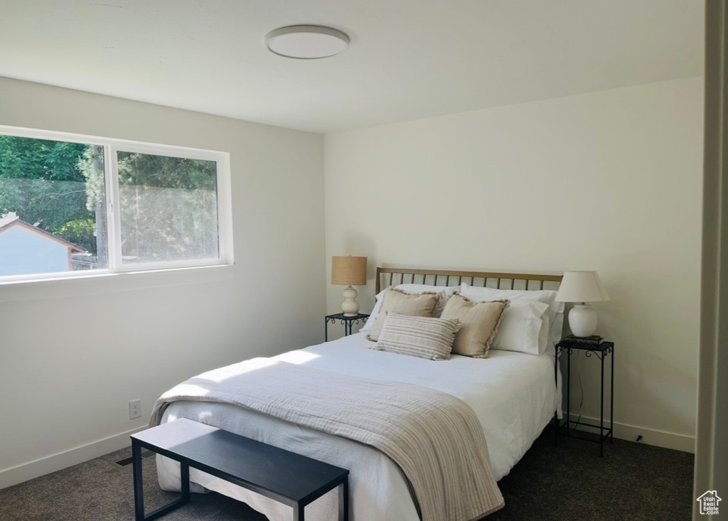 Bedroom with dark carpet and baseboards
