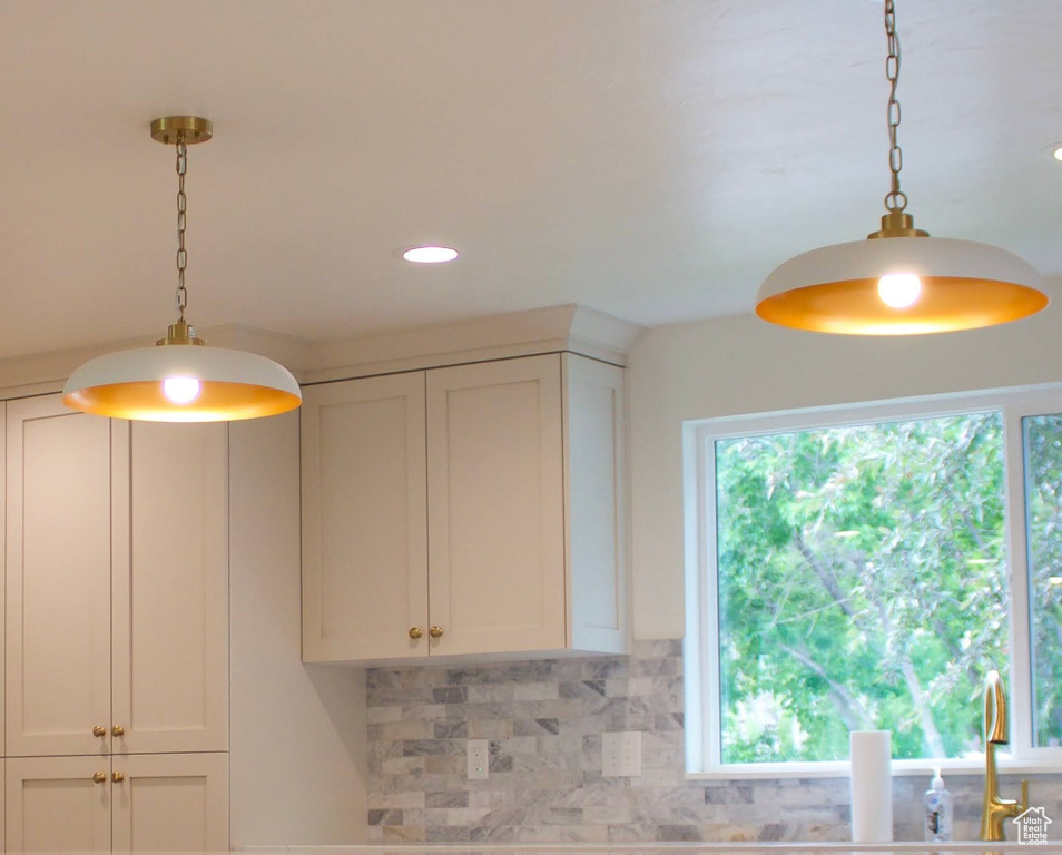 Kitchen view of pendant lighting, backsplash, white cabinets, and recessed lighting