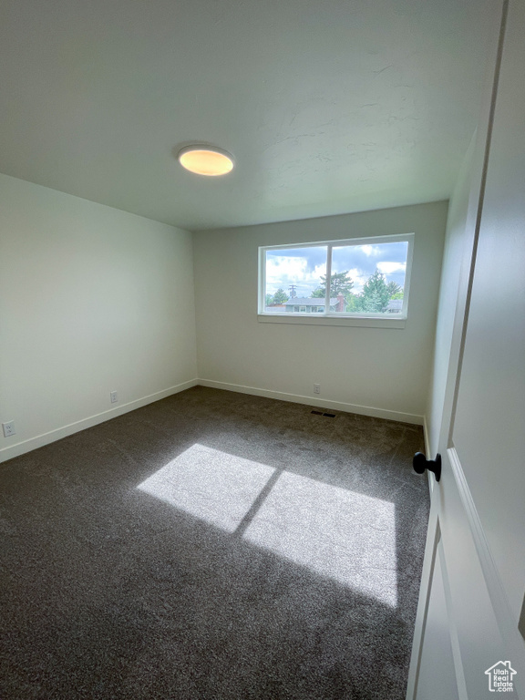 Spare room featuring carpet flooring and baseboards