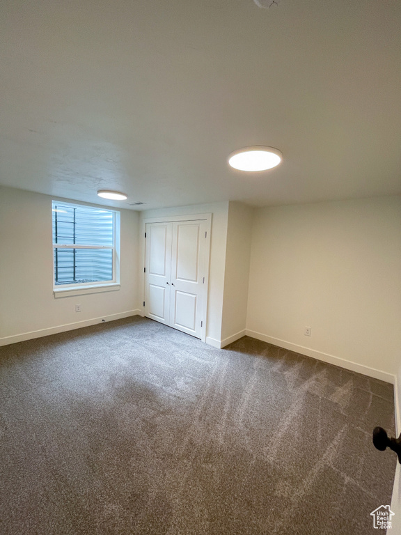 Unfurnished bedroom featuring dark colored carpet, baseboards, and a closet