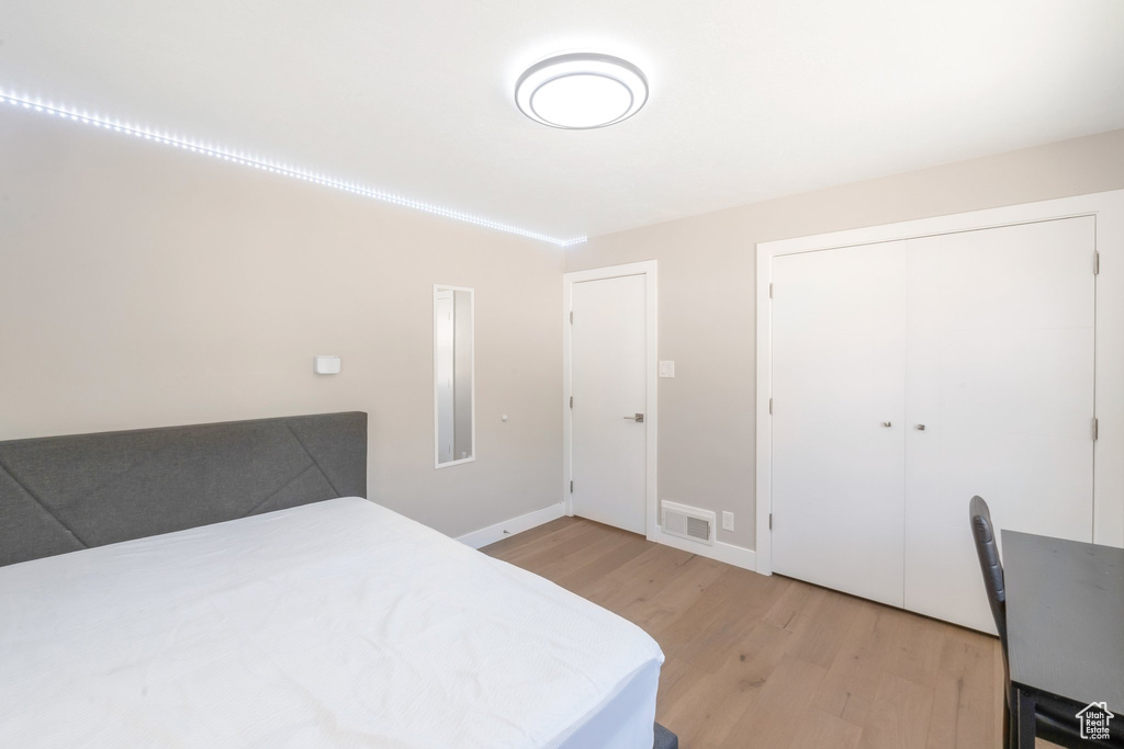 Bedroom with light wood finished floors, a closet, and baseboards