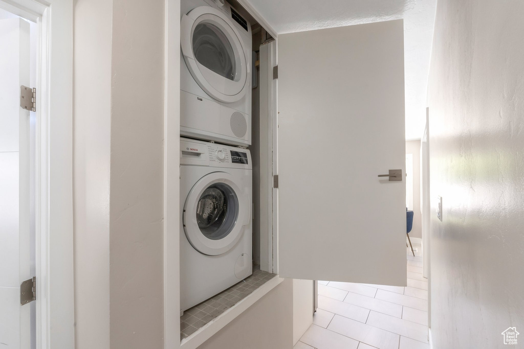 Laundry room featuring stacked washer / dryer and light tile patterned flooring
