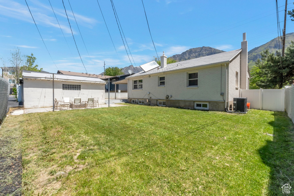 Back of house with cooling unit, a patio, a mountain view, and a chimney