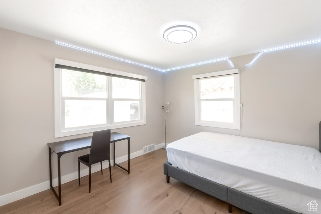 Bedroom featuring light wood-type flooring, multiple windows, and baseboards