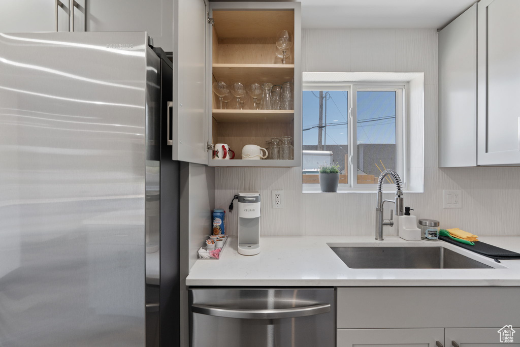 Kitchen featuring appliances with stainless steel finishes, a sink, light countertops, and white cabinetry