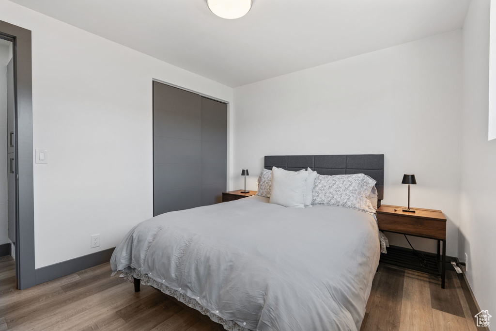 Bedroom with wood finished floors, a closet, and baseboards