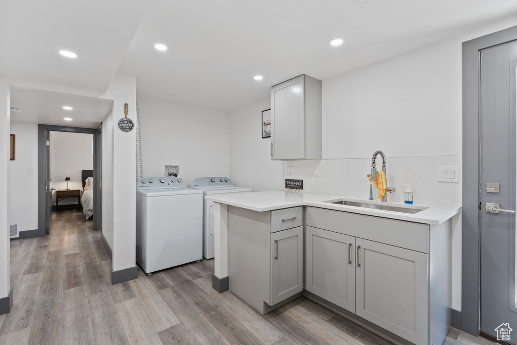 Washroom featuring washing machine and clothes dryer, light wood-style flooring, recessed lighting, and cabinet space