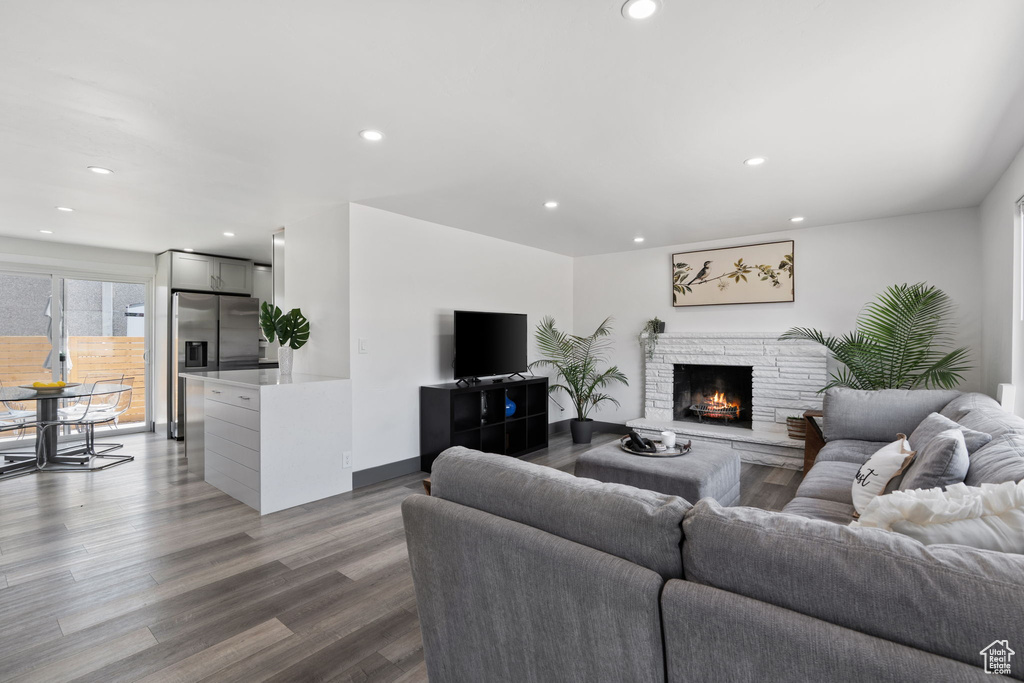 Living room featuring recessed lighting, wood finished floors, and a warm lit fireplace