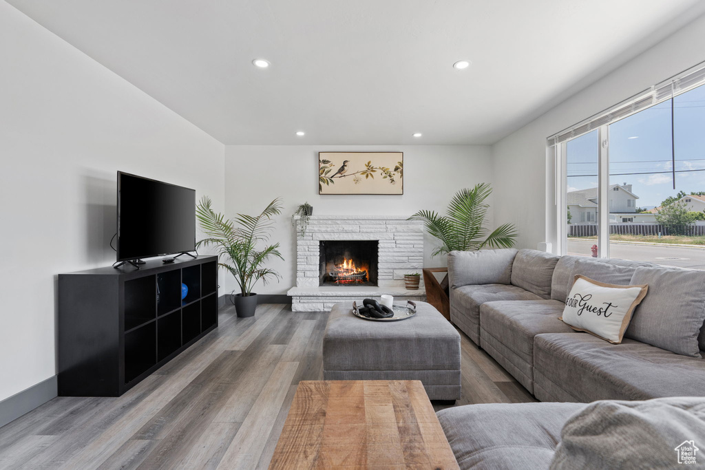 Living area with recessed lighting, wood finished floors, a stone fireplace, and baseboards