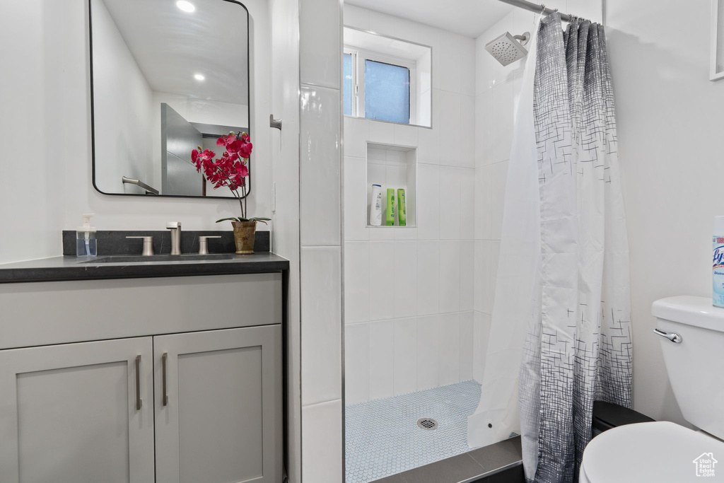 Full bathroom featuring toilet, tiled shower, and vanity