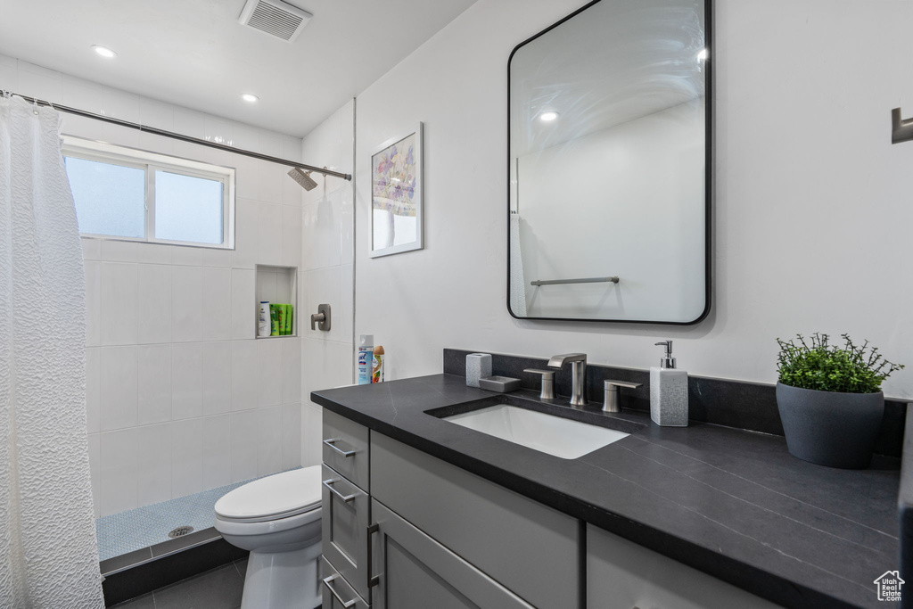 Bathroom featuring toilet, vanity, a tile shower, and recessed lighting