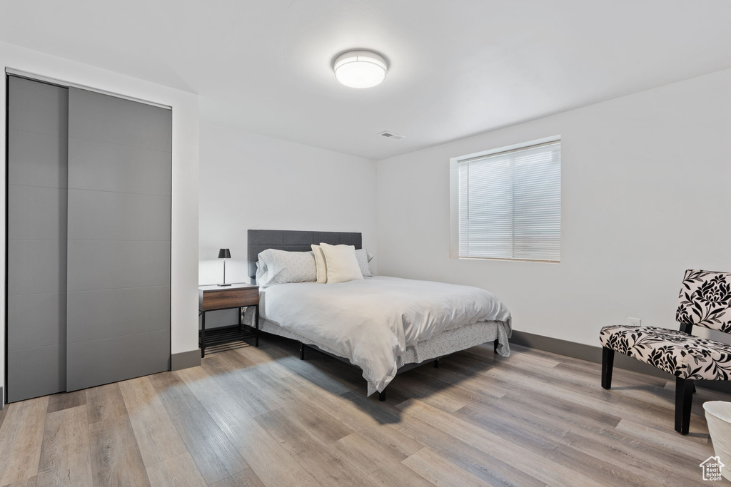 Bedroom with light wood-style floors, baseboards, and a closet