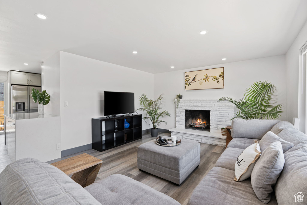 Living area with light wood-style flooring, recessed lighting, and a stone fireplace