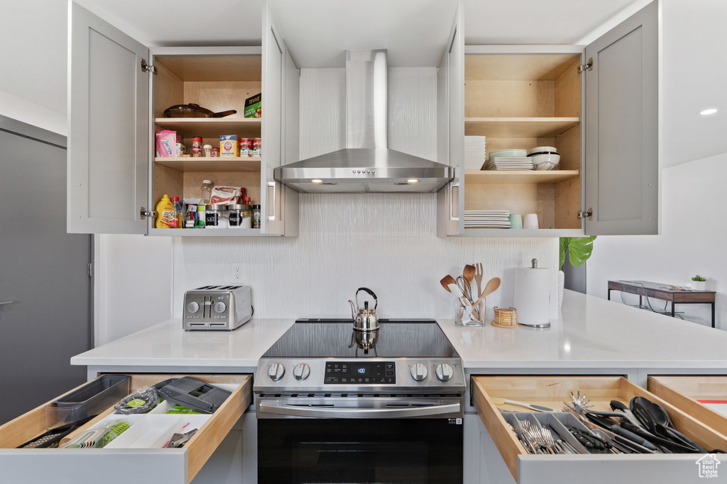 Kitchen featuring wall chimney exhaust hood, electric stove, open shelves, and light countertops