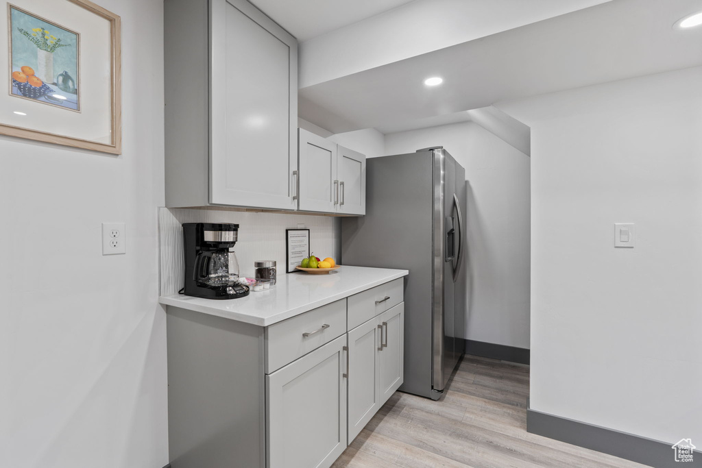 Kitchen with light countertops, light wood finished floors, stainless steel fridge, recessed lighting, and gray cabinets