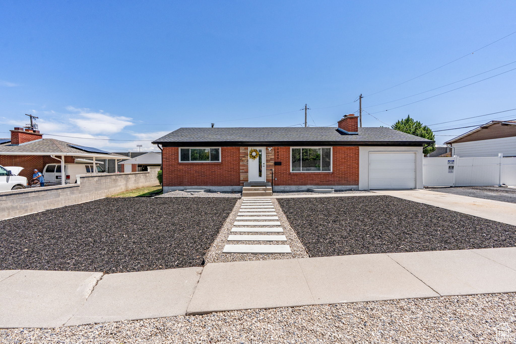Ranch-style house with driveway, brick siding, a garage, a chimney, and roof with shingles