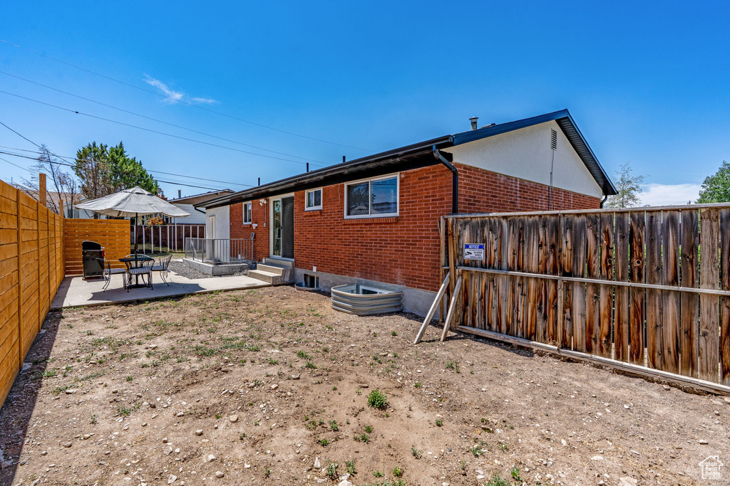 Back of house with brick siding, a patio, and a fenced backyard