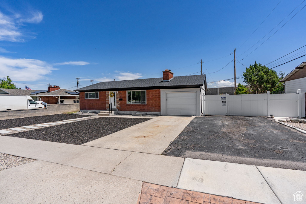 Ranch-style home with a garage, brick siding, driveway, and a chimney