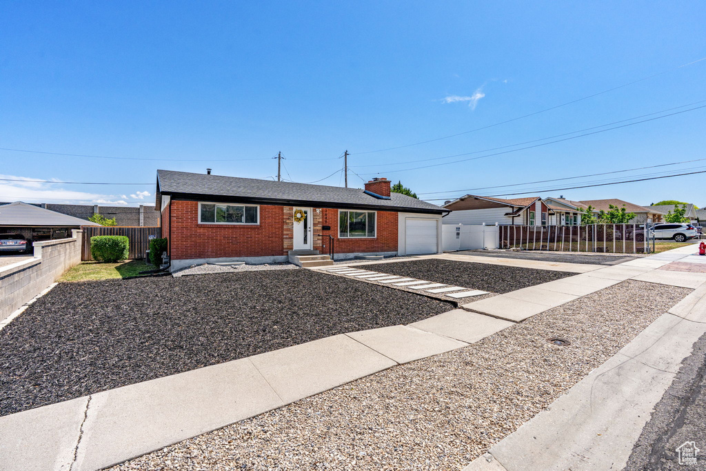 Single story home with brick siding, concrete driveway, a chimney, and an attached garage