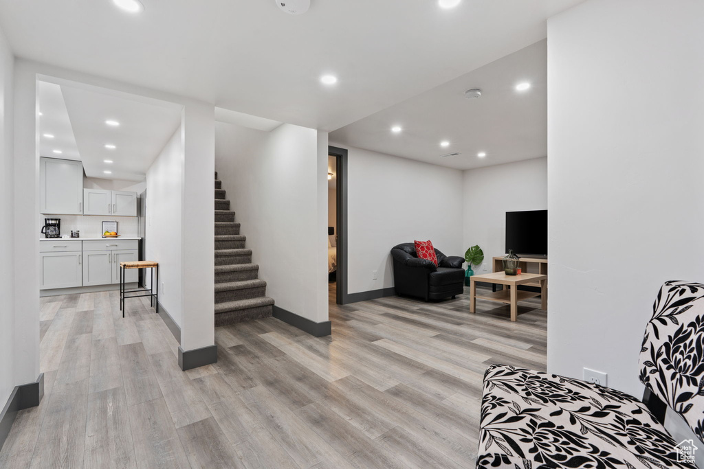 Living area with light wood finished floors, stairs, recessed lighting, and baseboards