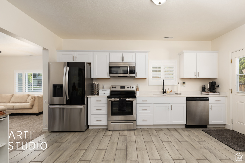 Kitchen featuring stainless steel appliances, a sink, light countertops, and light wood finished floors