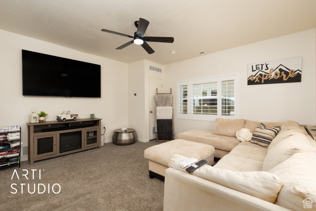 Carpeted living room featuring ceiling fan and baseboards