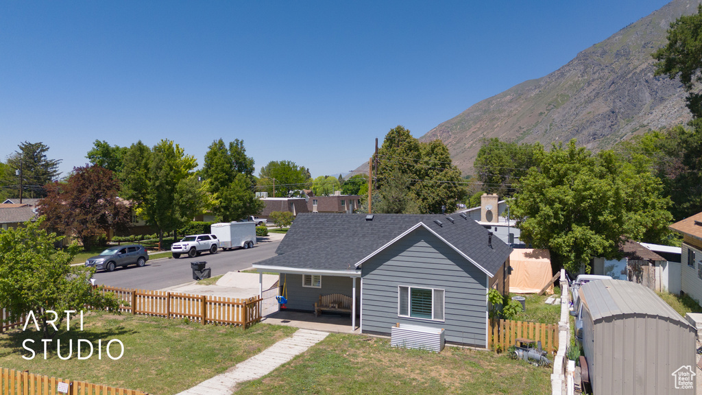 Back of property with a mountain view and roof with shingles