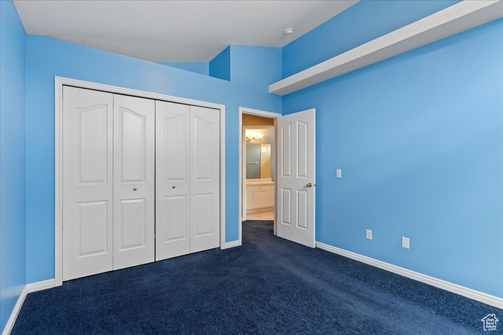Unfurnished bedroom featuring dark colored carpet, baseboards, and a closet
