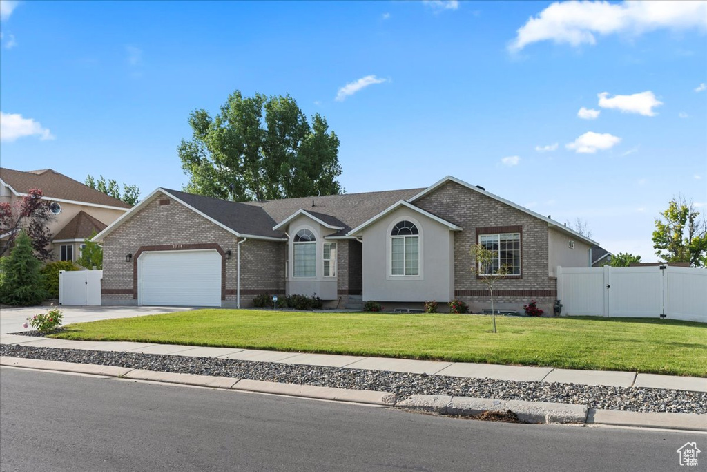 Ranch-style house featuring brick siding, a gate, an attached garage, and driveway
