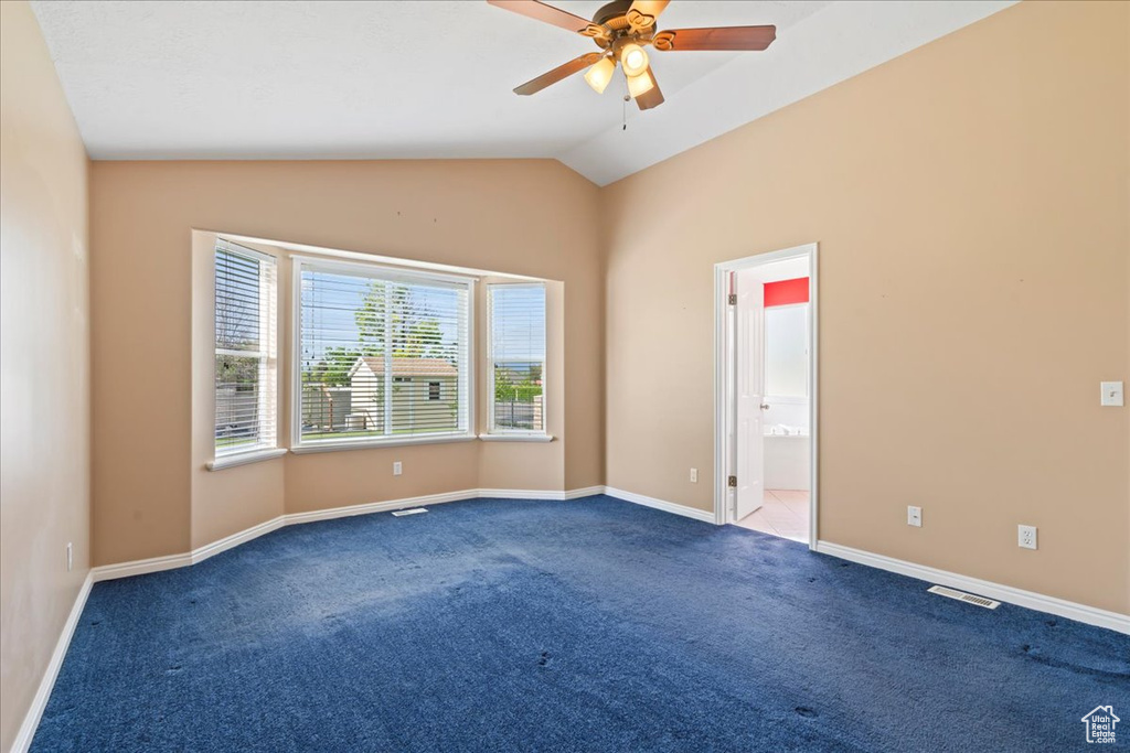 Carpeted spare room with lofted ceiling, ceiling fan, and baseboards