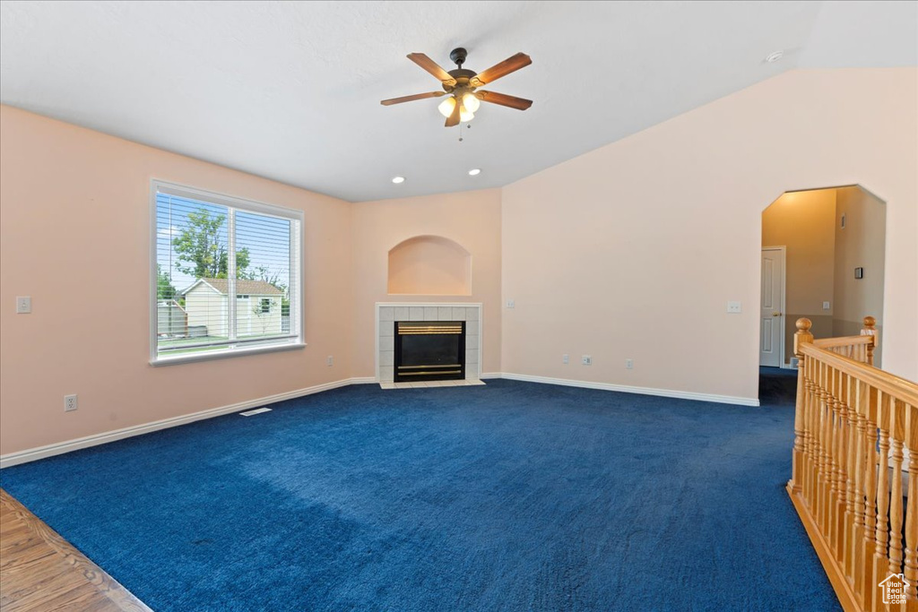 Unfurnished living room with ceiling fan, baseboards, a fireplace, carpet, and lofted ceiling