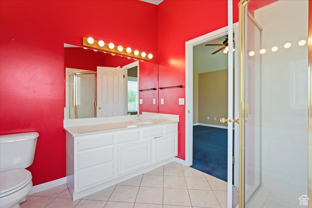 Bathroom with toilet, vanity, tile patterned flooring, ceiling fan, and a stall shower