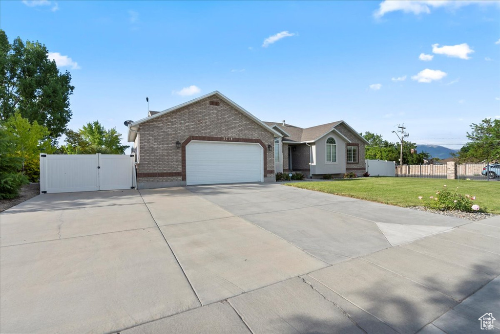 Ranch-style house featuring a gate, brick siding, concrete driveway, and an attached garage