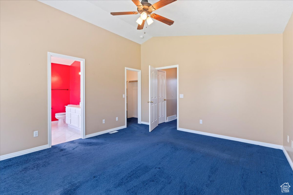 Unfurnished bedroom featuring carpet, baseboards, vaulted ceiling, a spacious closet, and ensuite bathroom