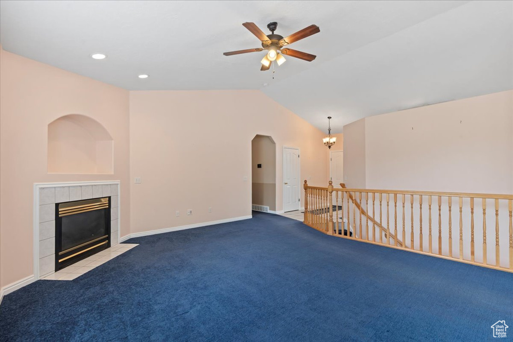 Unfurnished living room with carpet floors, a fireplace, vaulted ceiling, ceiling fan, and baseboards